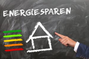 Symbolfoto Energiesparen/ Finger zeigt auf Gebäude, daneben Skala mit Energieeffizienzklassen