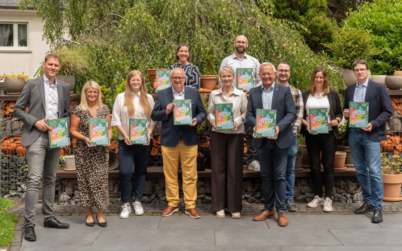 Gruppenfoto; Personen haben die Ausbildungsfibel in der Hand